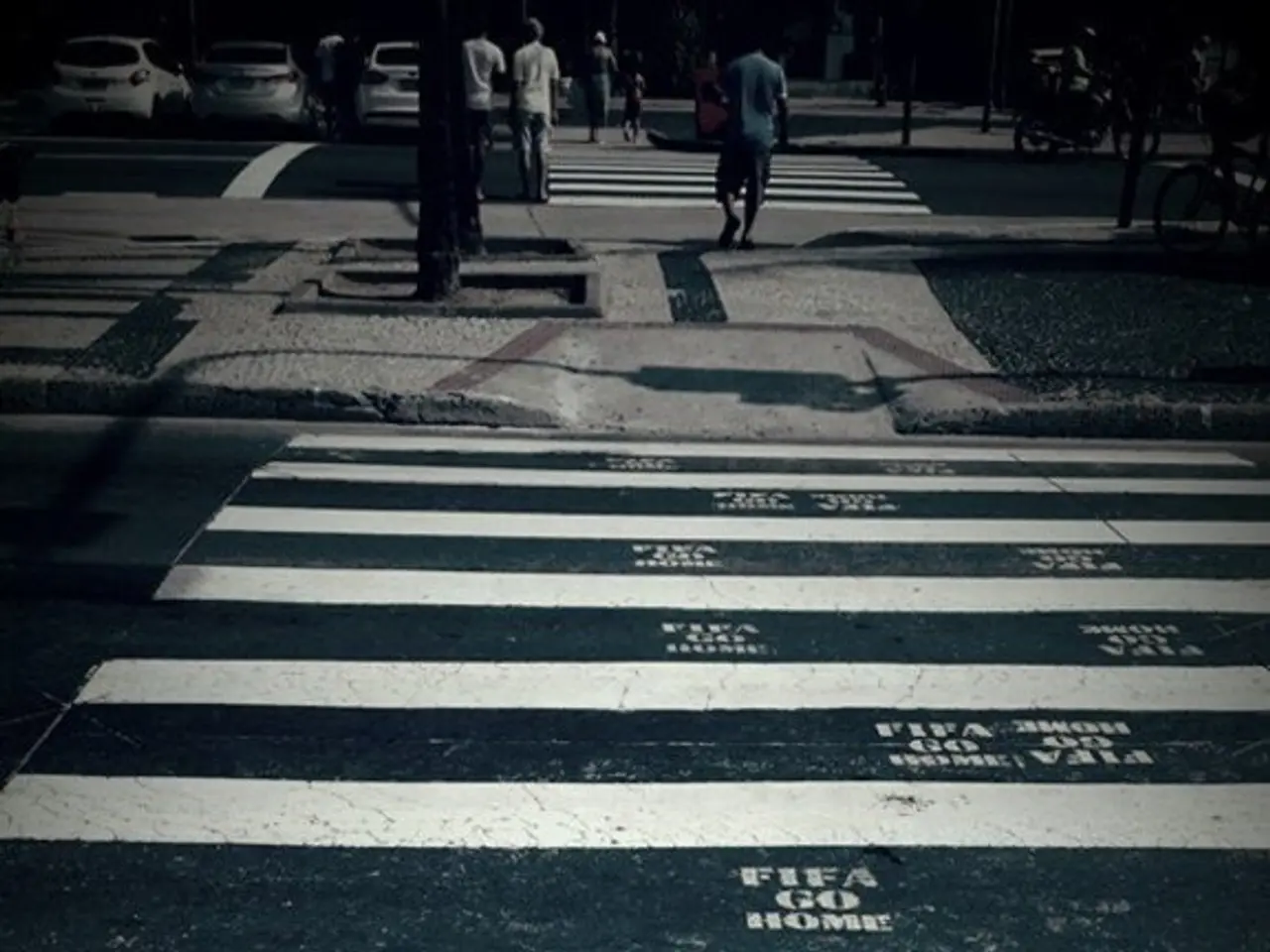 In this picture there are few people walking on zebra crossing and there are few cars in the left...