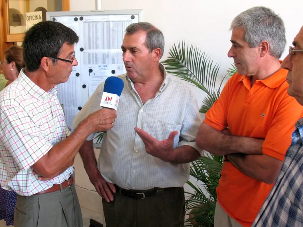 In this image there is a man in the middle who is interviewing the other person by holding the mic....