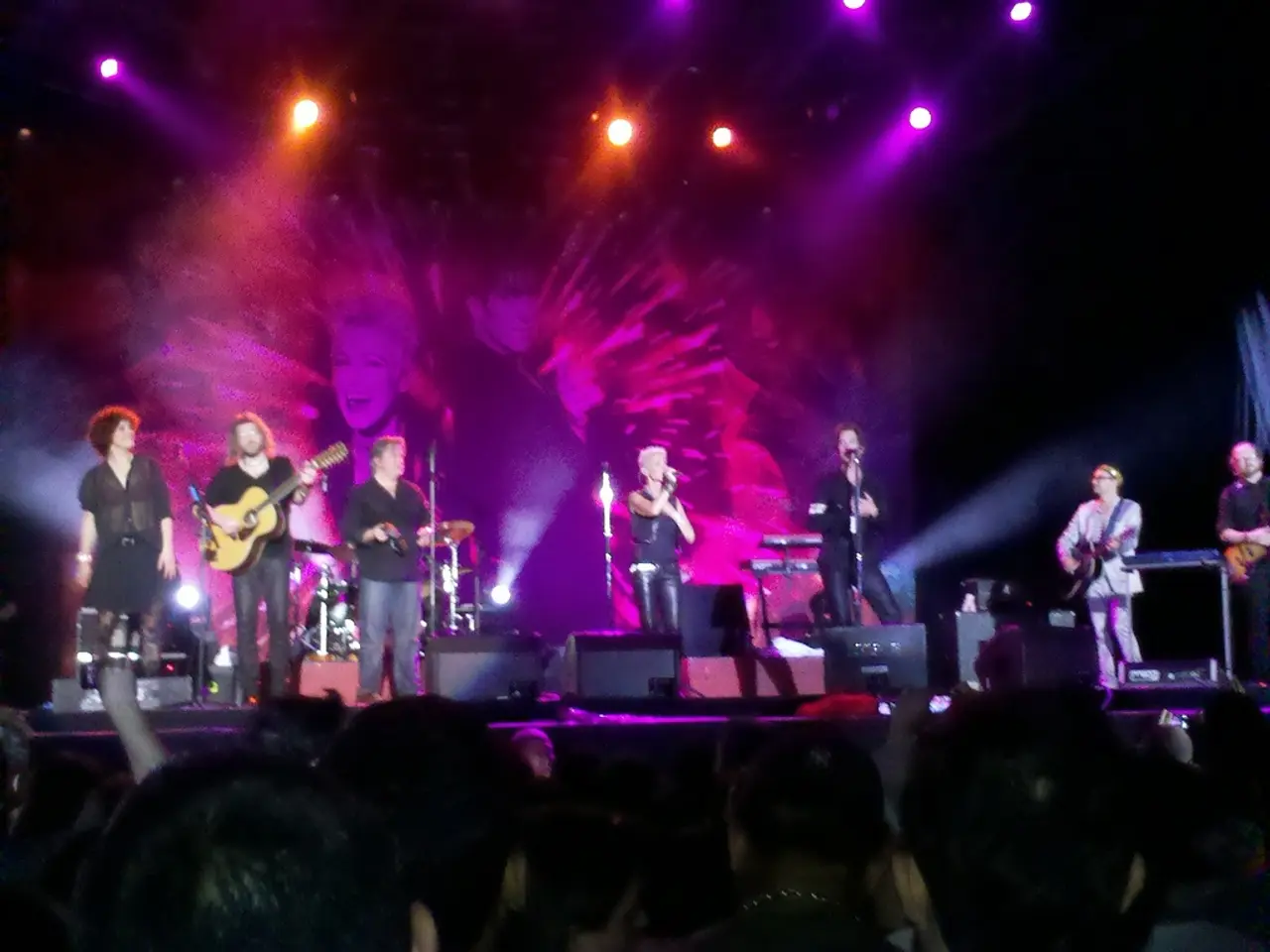 At the top we can see lights. On the background there is a screen. We can see all the persons...