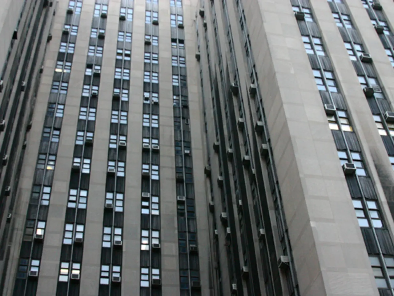 Here in this picture we can see a building with number of glass windows and AC present over there.