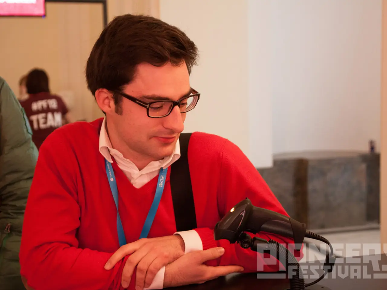 In this image there is a man. He is wearing an identity card. In front of him there is a...