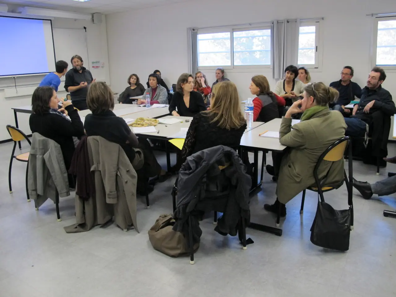 In this picture of group of people setting and discussing their and other two people standing over...