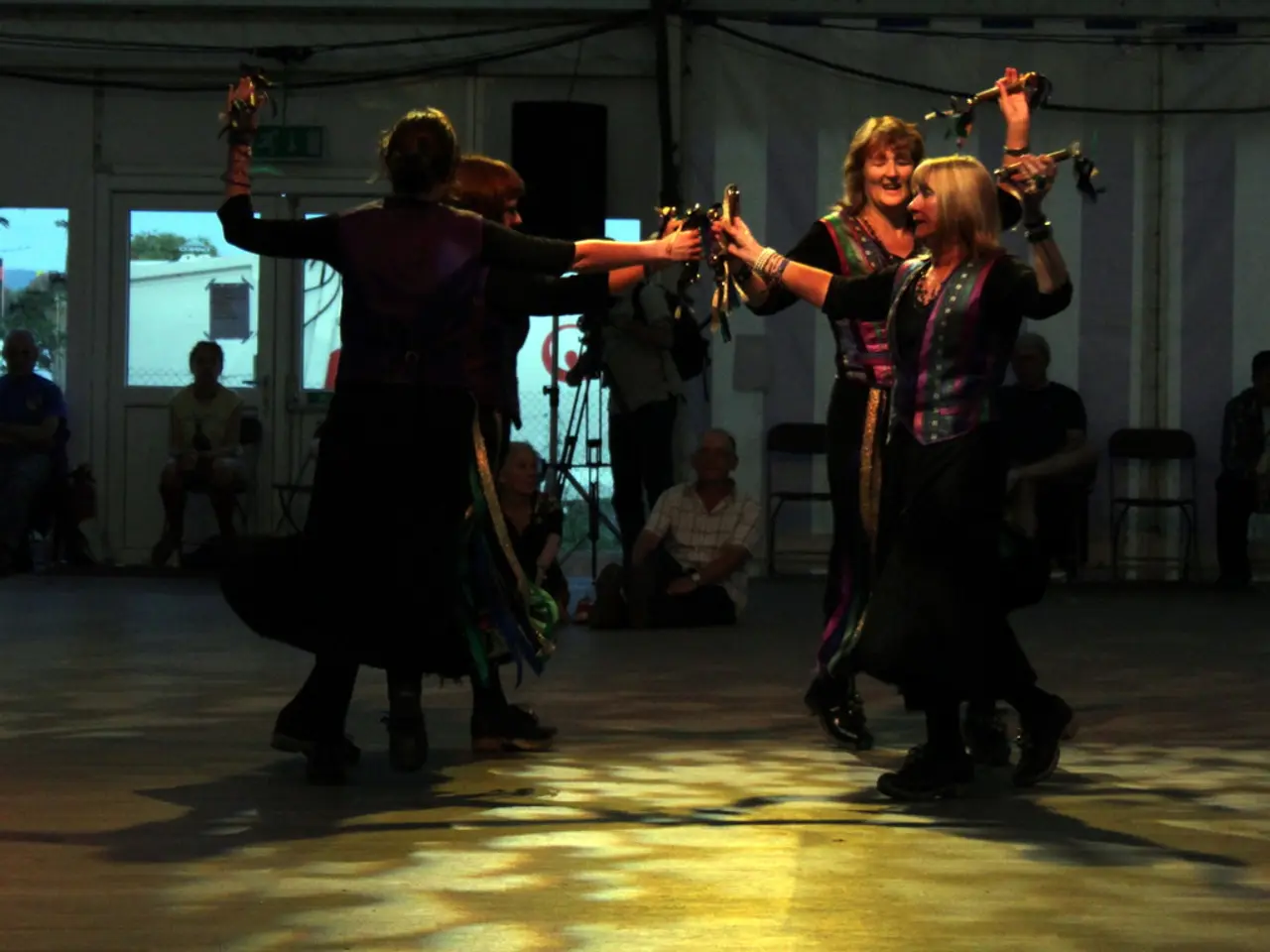 In this picture there are people dancing on the floor and holding objects. In the background of the...