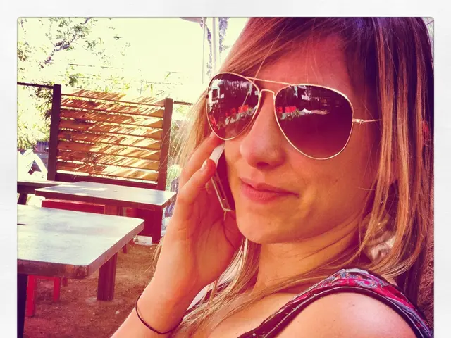 In this image see a woman who is holding a phone near to her ear and she is wearing shades and she...