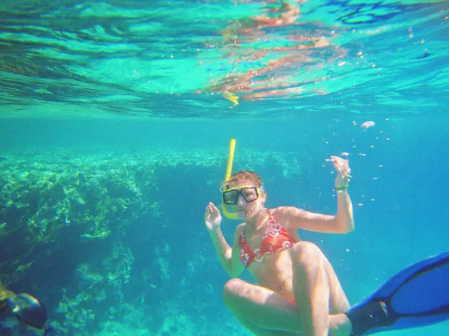 In this image we can see a woman wearing a swim dress. This image is taken under water.