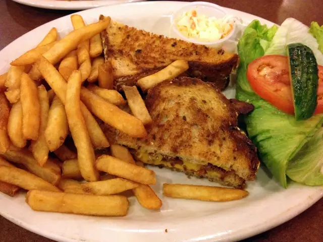 In this picture there is a plate in the center of the image, which contains french fries, salad,...