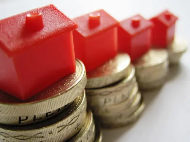 In this picture I can see there are red toys placed on the coins and they are placed on a white...