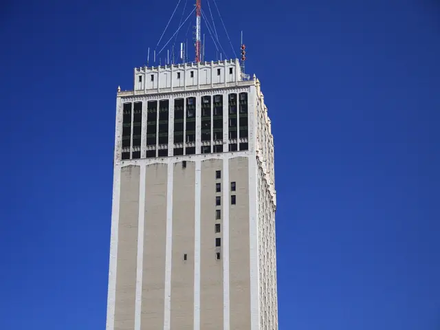 In front of the image there is a tower. On top of it there are antennas and signal poles. In the...